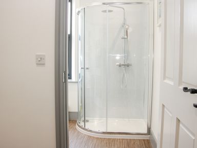 A bathroom with a glass enclosed corner shower and a window at The Farm in Presteigne