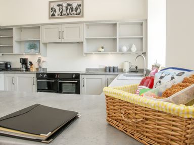 A kitchen with a black stove coffee maker and knife block on countertop with basket of food on island at The Farm in Presteigne