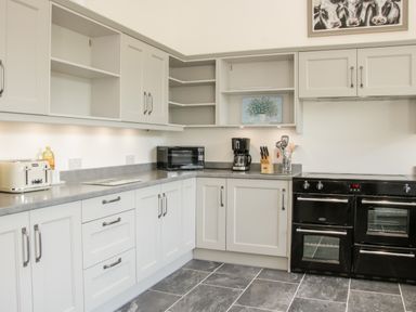 A kitchen with white cabinets a toaster microwave coffee maker black oven and utensils at The Farm in Presteigne