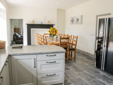 A kitchen with a dining table and chairs and a black refrigerator at The Farm in Presteigne