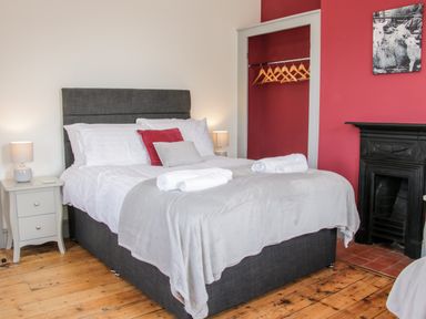 A bedroom with a double bed bedside tables lamps an open closet with hangers and a fireplace at The Farm in Presteigne