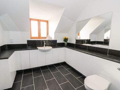 A bathroom with a sink toilet large mirror and rolled towels at Oakwood House in Rhayader