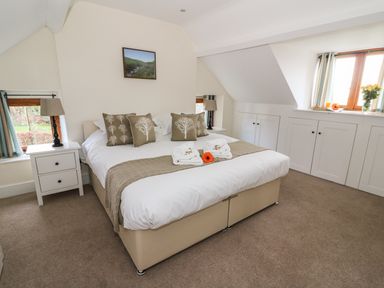 A bedroom with a bed pillows nightstands lamps and windows at Oakwood House in Rhayader