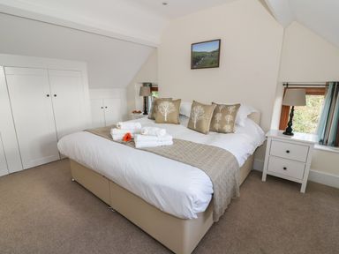 A bedroom with a double bed with tree pattern cushions and bedside tables with lamps at Oakwood House in Rhayader