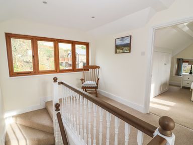 A stairway landing with a wooden chair cushion and framed picture on the wall at Oakwood House in Rhayader