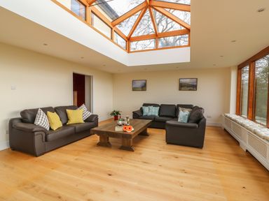 A living room with two leather sofas a wooden coffee table and a large skylight window at Oakwood House in Rhayader