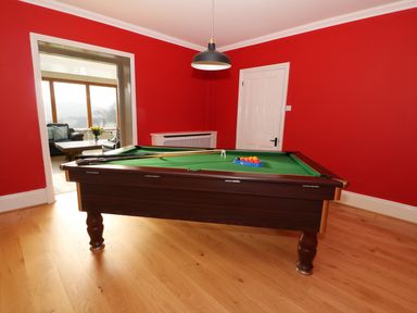 A room with a pool table green cloth and red walls at Oakwood House in Rhayader