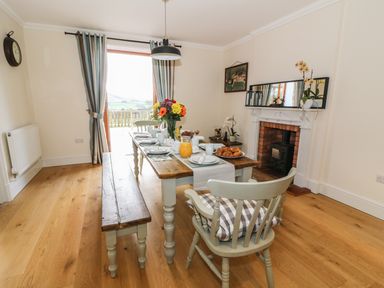 A dining room with a wooden table set for breakfast near a fireplace at Oakwood House in Rhayader