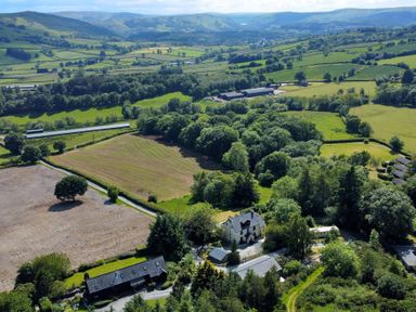 An aerial view of green fields trees and houses in a rural area at Oakwood House in Rhayader