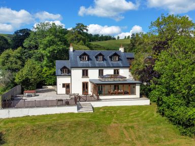 A three story house with a patio and garden surrounded by trees at Oakwood House in Rhayader