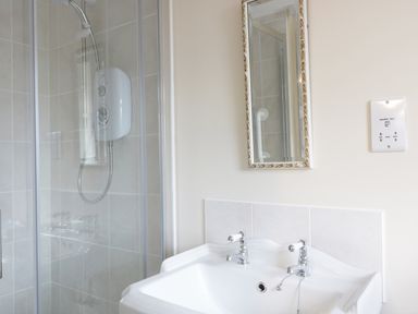 A bathroom with a shower enclosure a sink with two taps and a mirror at Broadway Lands Farm in Little Dewchurch