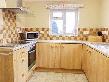 A kitchen with a microwave oven stovetop sink knives and wooden cabinets at Broadway Lands Farm in Little Dewchurch