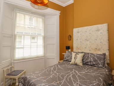 A bedroom with a bed and a window with blinds at Apartment 3 in Tenby
