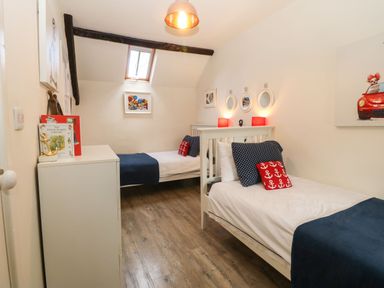 A bedroom with two single beds a white dresser and framed art on the walls at Y Bwthyn Ty Du in Pwllheli