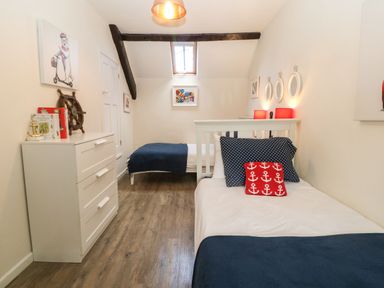 A bedroom with two single beds a white chest of drawers and nautical-themed decor at Y Bwthyn Ty Du in Pwllheli
