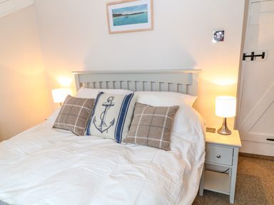 A bedroom with a bed with three pillows and two bedside tables with lamps at Blue Anchor in Fraddon