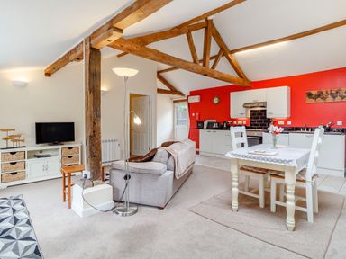 An open plan living space with a kitchen dining area and sitting area with exposed wooden beams at The Hen House in Diss near Gissing