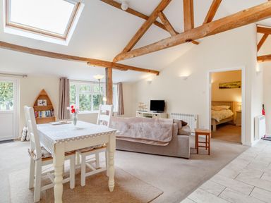 A living room with a dining table and chairs a sofa a television and visible bedroom at The Hen House in Diss near Gissing