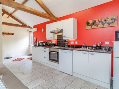 A kitchen with white cabinets appliances and wooden beams on the ceiling at The Hen House Diss near Gissing
