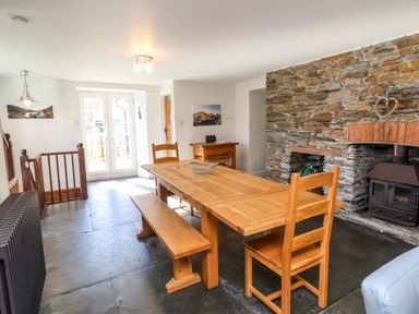A dining room with wooden table and chairs near a stone fireplace at Tower House in Boscastle