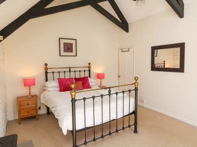 A bedroom with a metal bed frame wooden nightstands with lamps and a mirror on the wall at Tower House in Boscastle