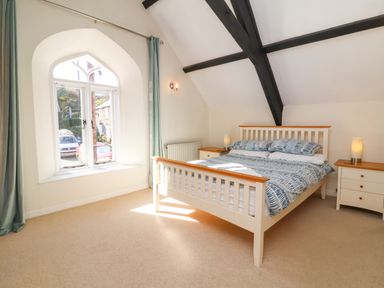 A bedroom with a double bed two bedside tables and a window with curtains at Tower House in Boscastle