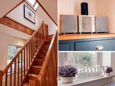 A wooden staircase with a framed picture above and a window beside it a small stereo system on a blue cabinet a windowsill with two potted plants and a decorative family sign at Cross Syke Barn in Loxhore near Barnstaple