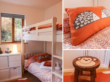A children's bedroom with white bunk beds orange bedding and a wooden stool with a monkey face at Cross Syke Barn in Loxhore near Barnstaple