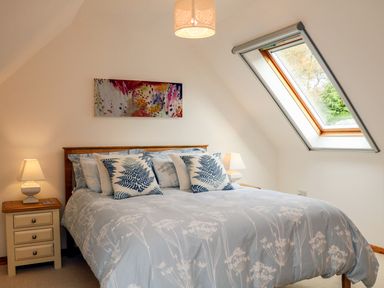 A bedroom with a double bed two bedside tables lamps window and wall art at Cross Syke Barn in Loxhore near Barnstaple