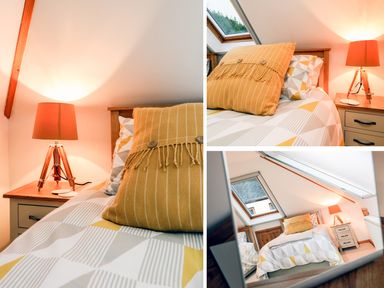 A bedroom with a bed featuring geometric patterned bedding and a mustard yellow pillow next to a wooden bedside table with a lamp at Cross Syke Barn in Loxhore near Barnstaple