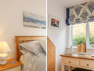 A bedroom with a wooden bed and floral bedding and a desk with a mirror and window at Cross Syke Barn in Loxhore near Barnstaple