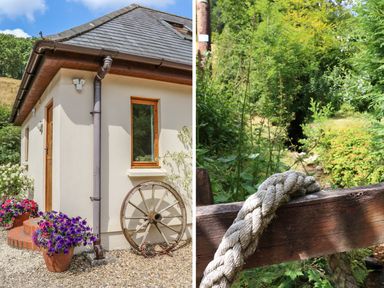 An exterior corner of a house with flower pots and a wooden wheel and a close-up of a rope on a wooden railing with green plants in the background at Cross Syke Barn in Loxhore near Barnstaple