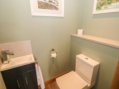 A small bathroom with a toilet and a sink with a towel hanging next to it at Harmon Vale in Solva