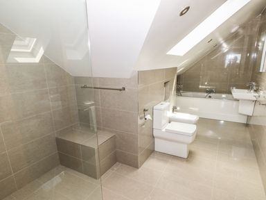 A bathroom with a toilet bidet bathtub and sink under a slanted ceiling at Harmon Vale in Solva