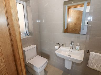 A bathroom with a toilet a wall-mounted sink and a mirror at Harmon Vale in Solva