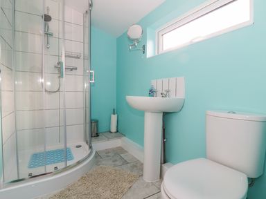 A bathroom with a shower cubicle sink toilet and a small window at The Nest Box in Diss