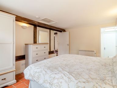 A bedroom with a bed a chest of drawers a wardrobe and a mirror at The Nest Box in Diss