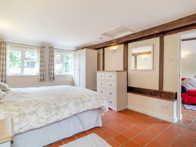 A bedroom with a bed a wardrobe a chest of drawers and a window with curtains at The Nest Box in Diss