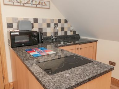 A kitchen counter with a microwave kettle sink and stovetop at St Dolmen in Embleton