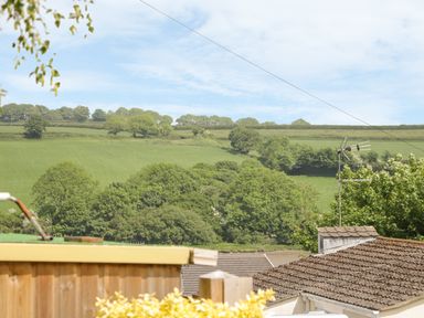 View of a green hillside with trees and rooftops of houses in the foreground at 54 The Moorings in St Dogmaels