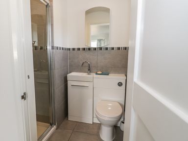 A bathroom with a toilet sink unit and a shower with a glass door at 54 The Moorings in St Dogmaels