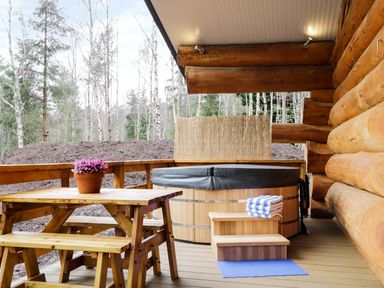 A wooden deck with a picnic table and a hot tub next to a log cabin at Moorhen Lodge in North Kessock