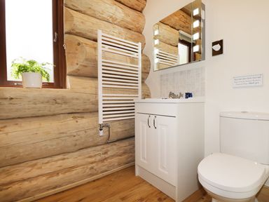 A bathroom with a toilet sink cabinet mirror towel radiator and a window with a plant on the sill at Moorhen Lodge in North Kessock