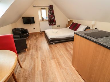 A bedroom with a bed two chairs a wall mounted tv and a countertop at St  Cruz in Embleton