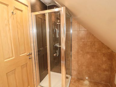 A bathroom with a glass enclosed shower cubicle and tiled walls at St Cruz in Embleton