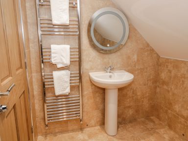 A bathroom with a pedestal sink mirror and towel rail with towels at Newton View in Embleton