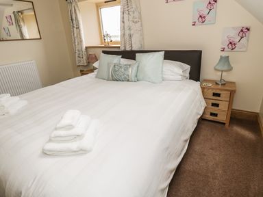 A bedroom with a double bed pillows bedside tables and lamps at Newton View in Embleton