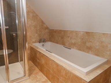 A bathroom with a bathtub and a glass shower enclosure at Mill View in Embleton