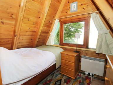 A small wooden bedroom with a single bed a nightstand with a lamp a window and curtains at Apple Tree Lodge in Gillingham