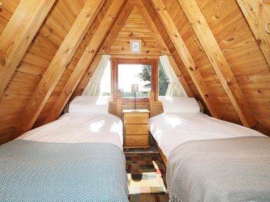 A bedroom with two single beds a wooden nightstand and a window in an attic at Apple Tree Lodge in Gillingham
